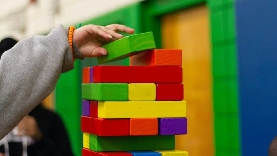 hand adding colorful blocks to a playful structure